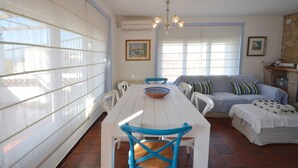 A dining area with a white table, blue chairs, and a chandelier. There is a sofa with striped pillows and a bed with a patterned blanket. - Holiday rental townhouse with swimming pool in Begur, Centre (Begur)