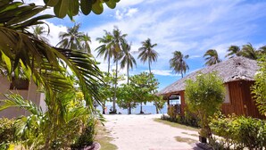 A resort with thatched-roof huts, palm trees, and a sandy pathway leading to the beach. - Bruce Beach Resort (San Juan)