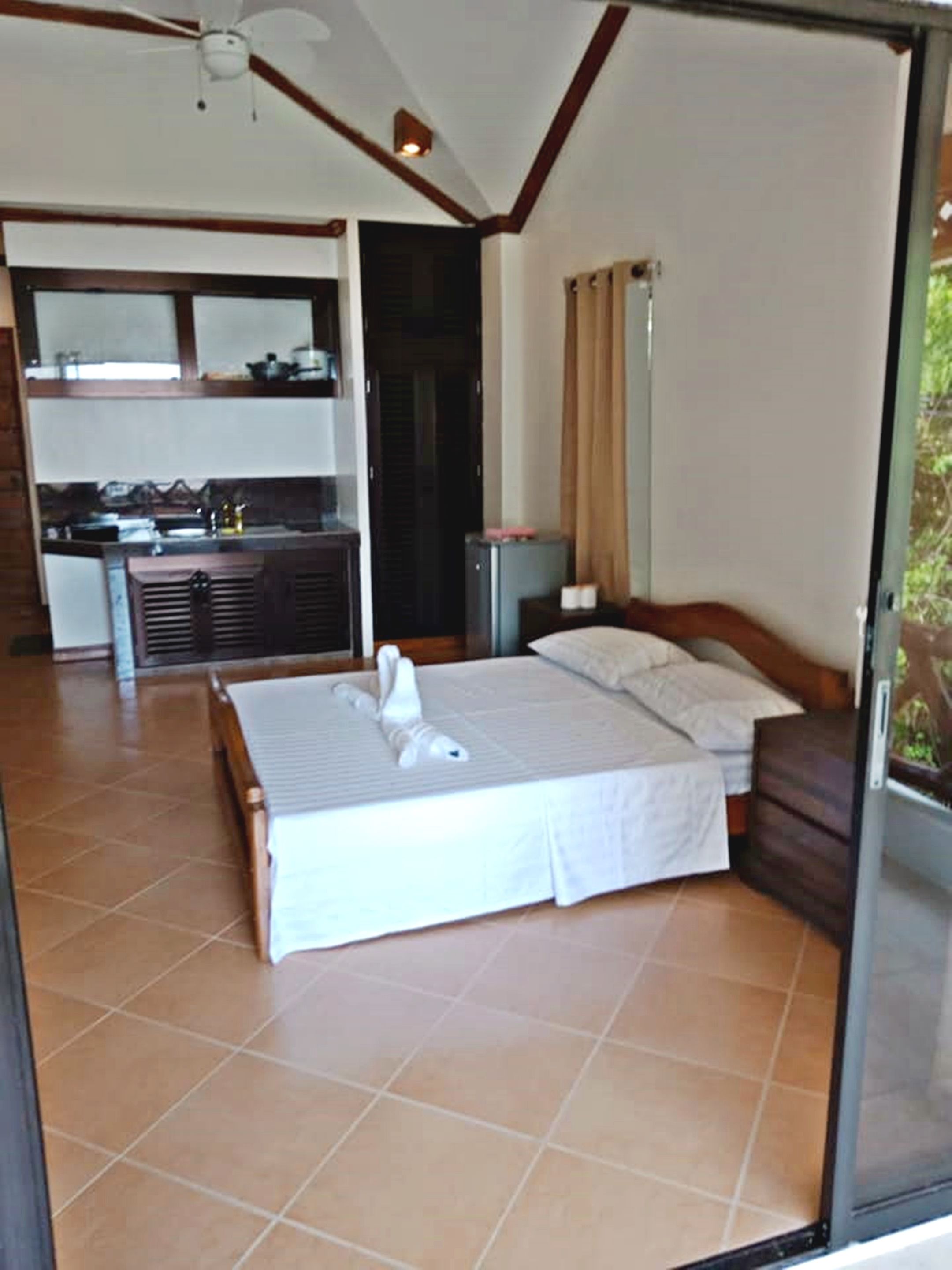 A bedroom with a bed, a nightstand, and a view of the outside.