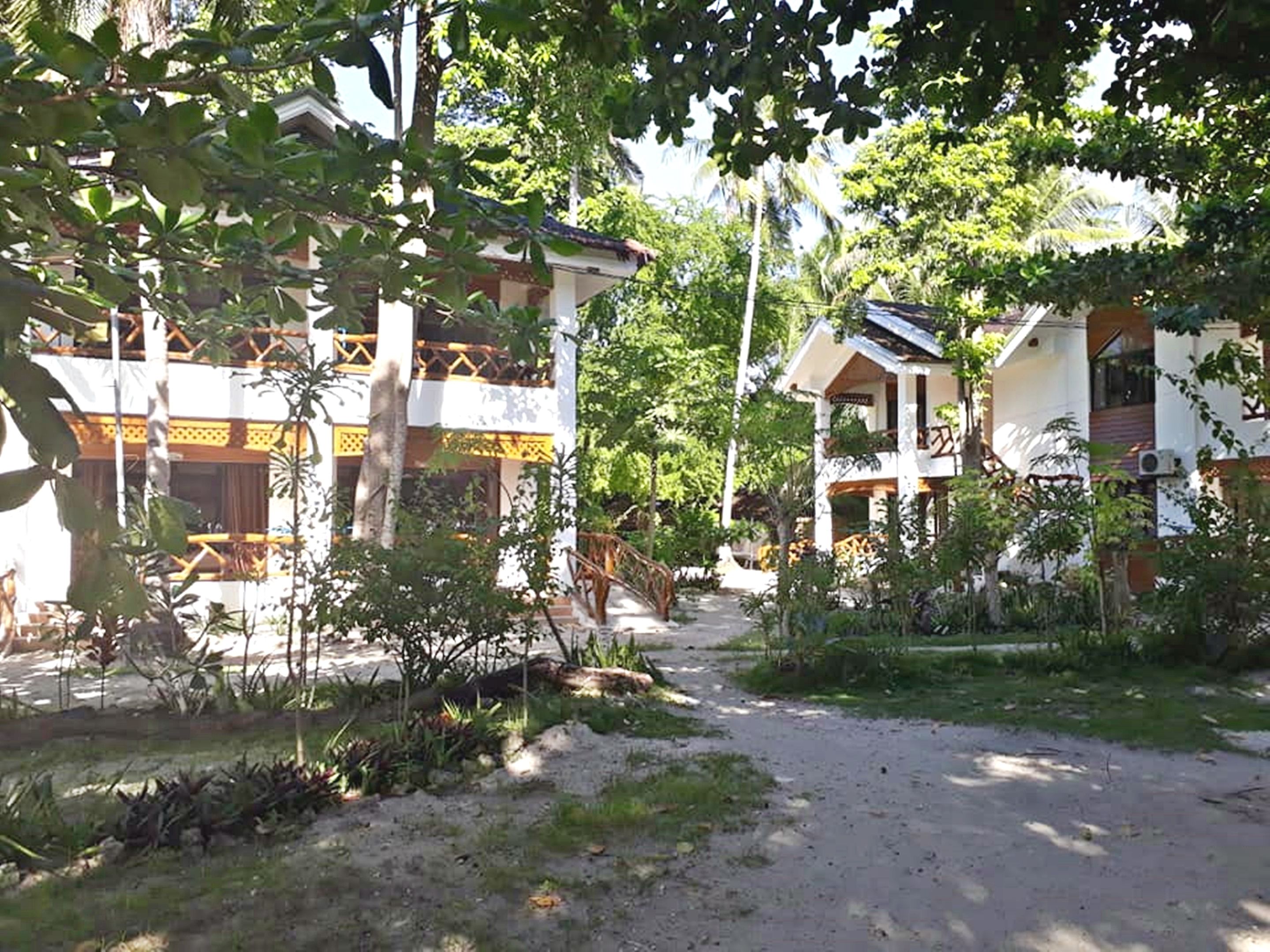 A pathway leading to a building with a traditional architectural style, surrounded by lush greenery and trees.