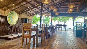 A restaurant with a rustic wooden interior, hanging wicker lamps, and a stage for performances. - Bruce Beach Resort (San Juan)