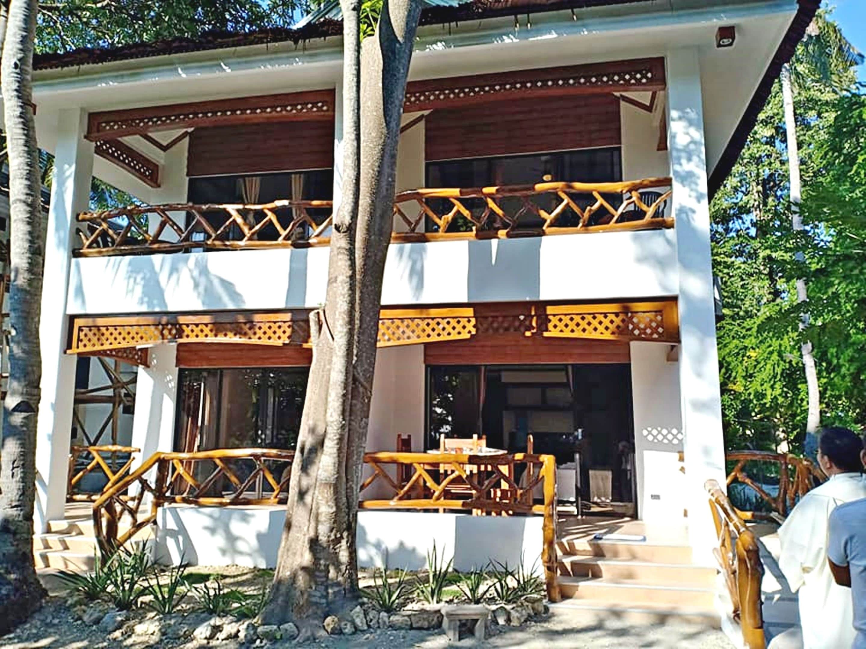 A two-story building with a balcony, wooden railings, and a staircase leading to the entrance.