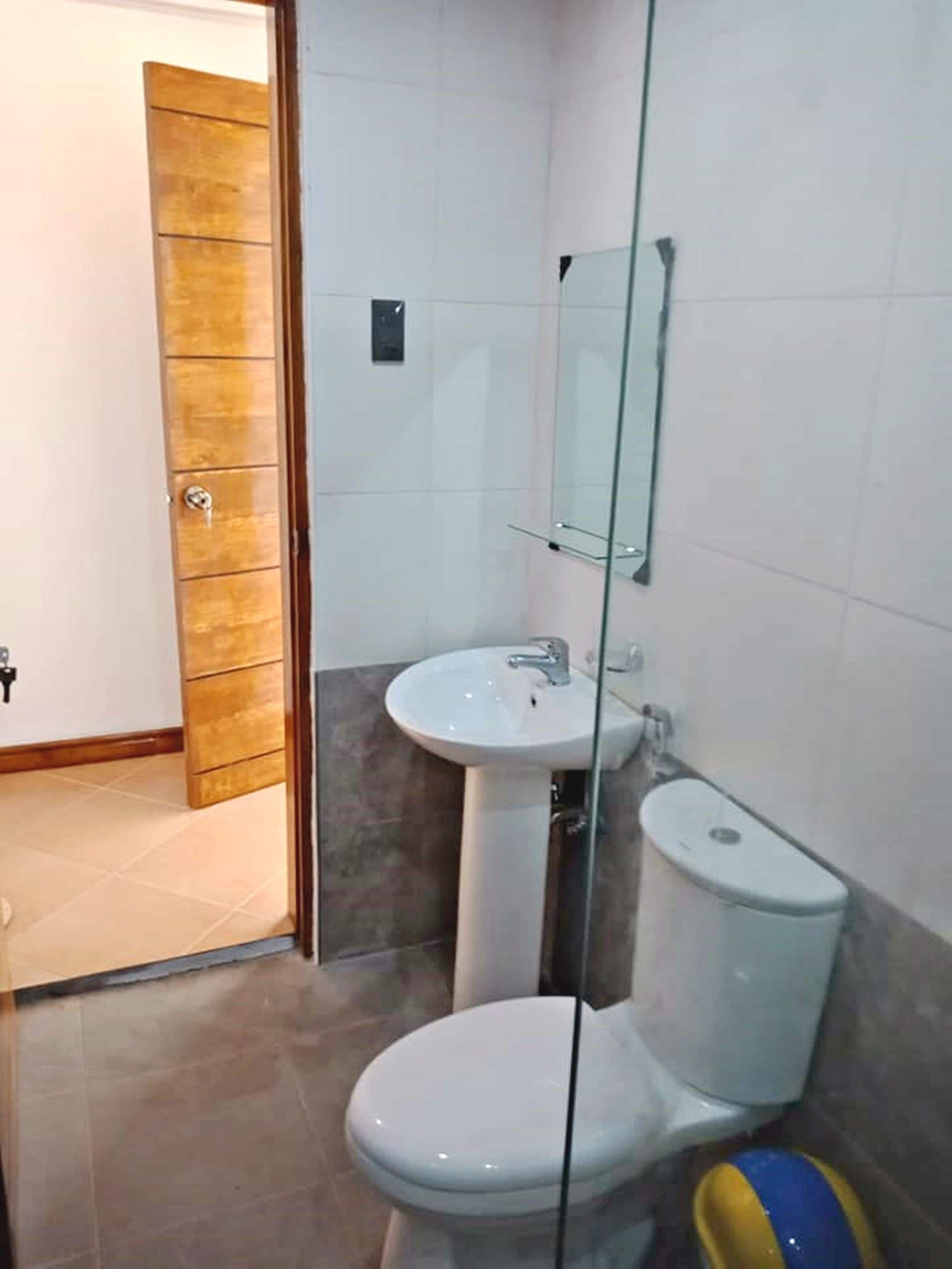 A bathroom with a toilet, sink, and glass shower enclosure.