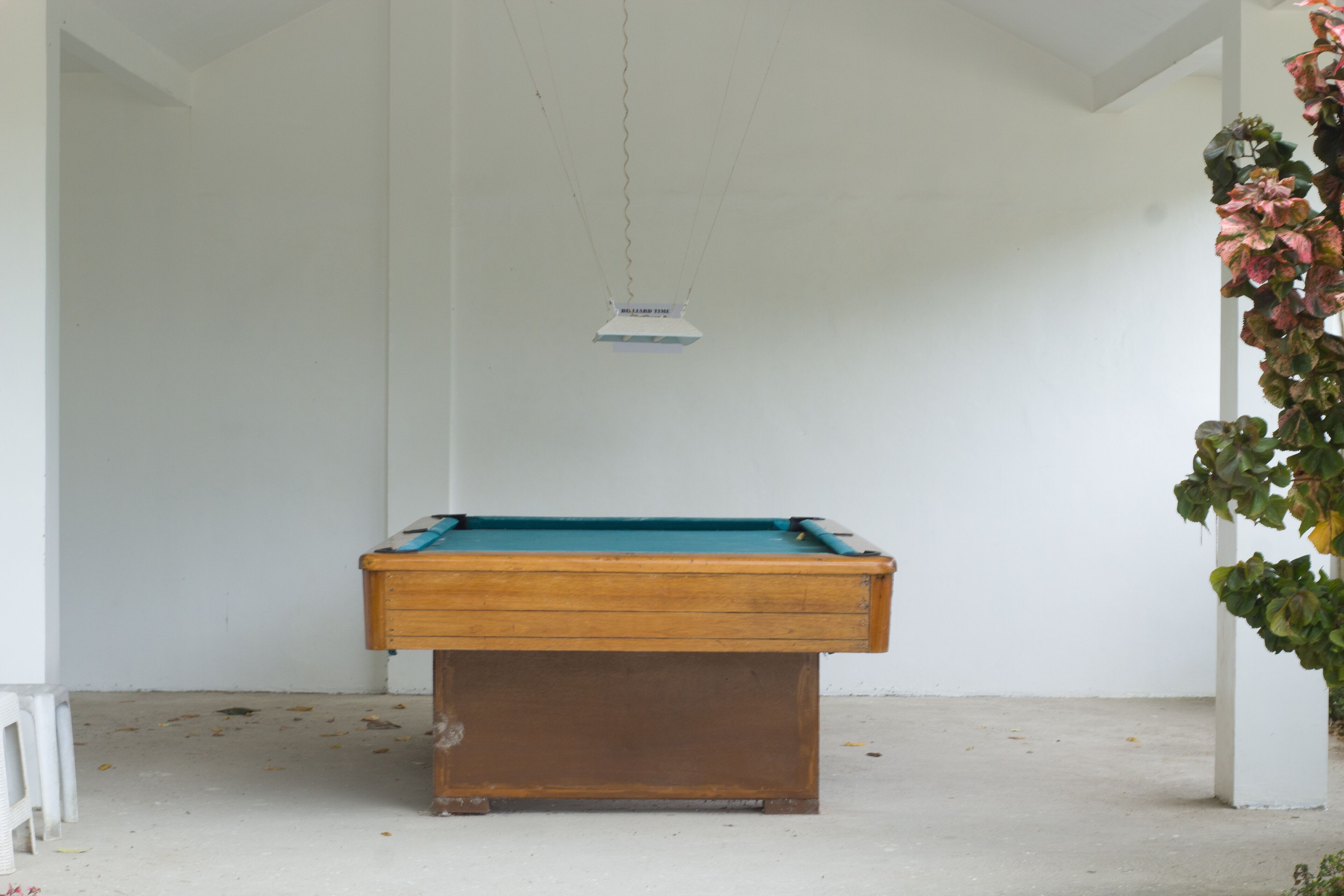 A pool table in a room with white walls and a concrete floor.