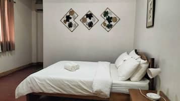 A neatly made bed with white bedding and pillows, a bedside table with a lamp, and three wall-mounted decorative items.