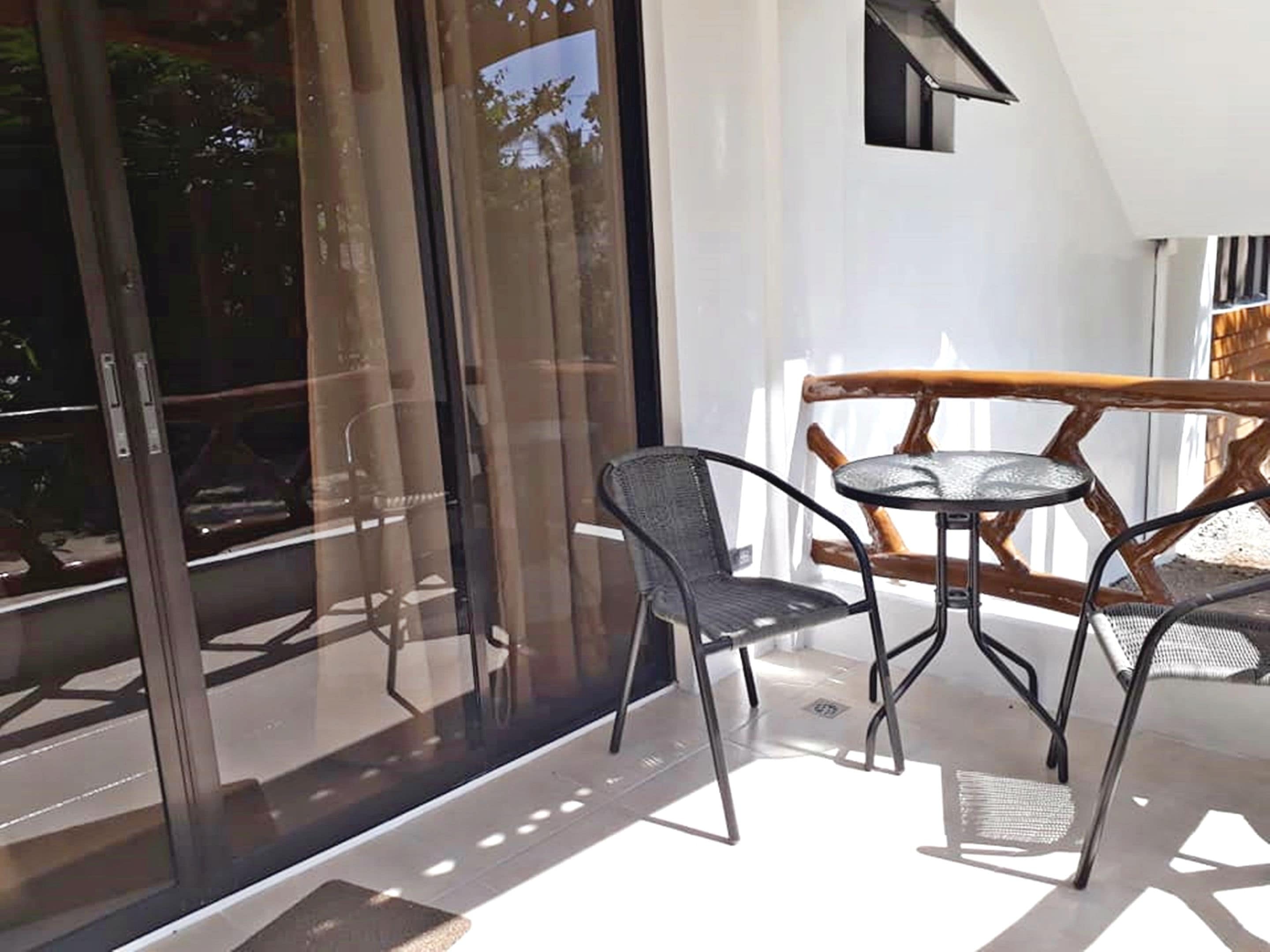 A balcony with a glass door, a small round table, and two chairs.