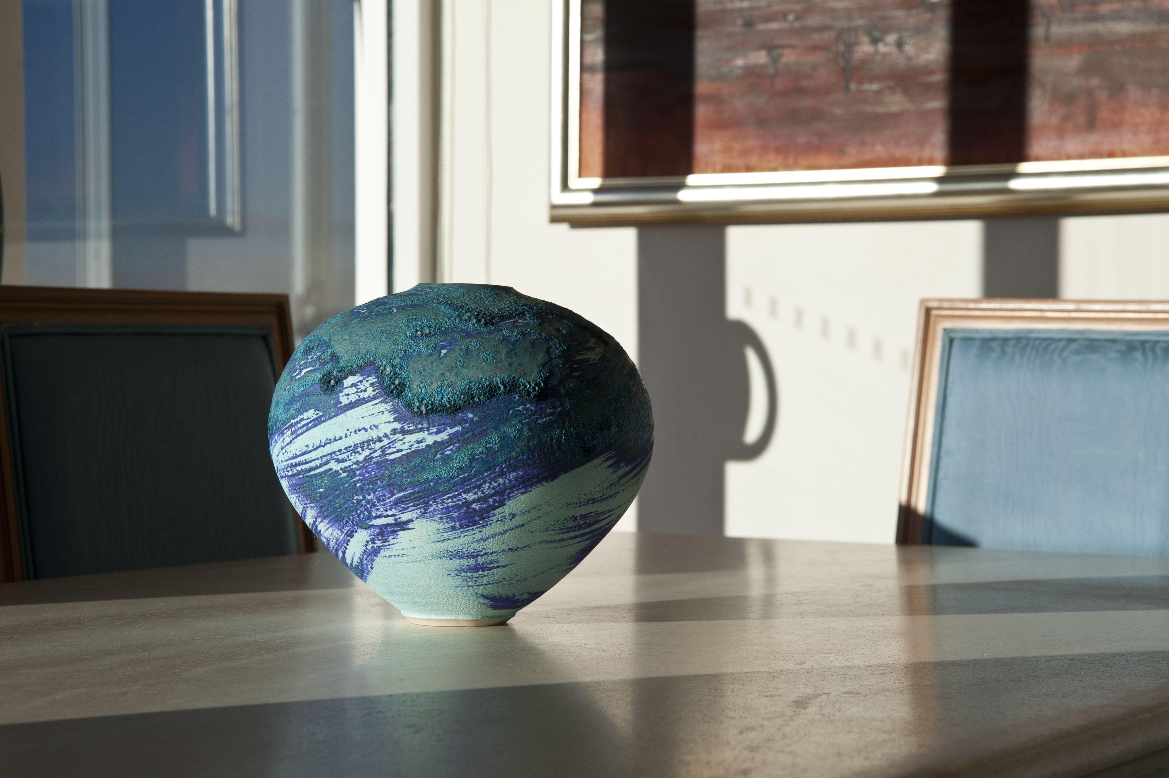 A ceramic bowl on a table with a window in the background.