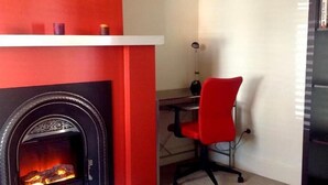 A room with a fireplace, a red office chair, and a desk. - Waterloo Cottage (Battery Point)