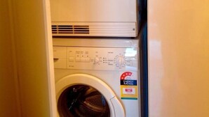 A compact washer and dryer unit with a control panel and a visible energy rating label. - Waterloo Cottage (Battery Point)