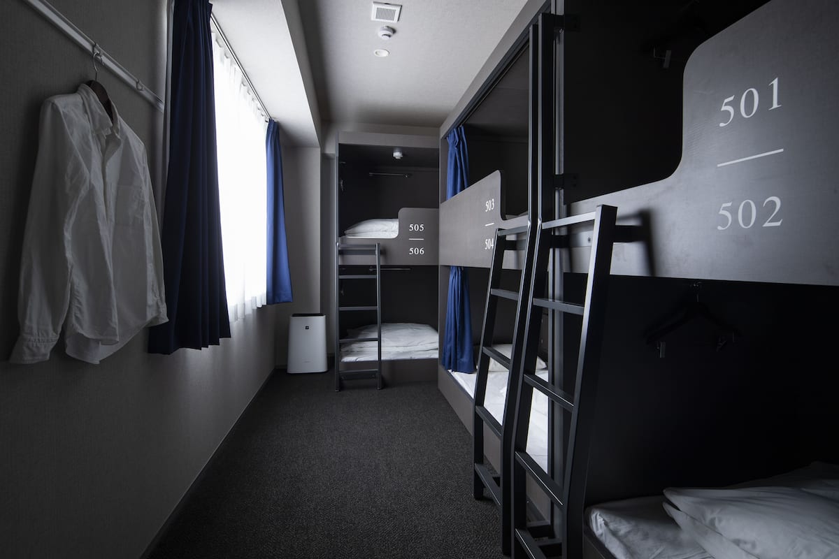 Een kleine hotelkamer met stapelbedden, een bureau en een kledingkast.