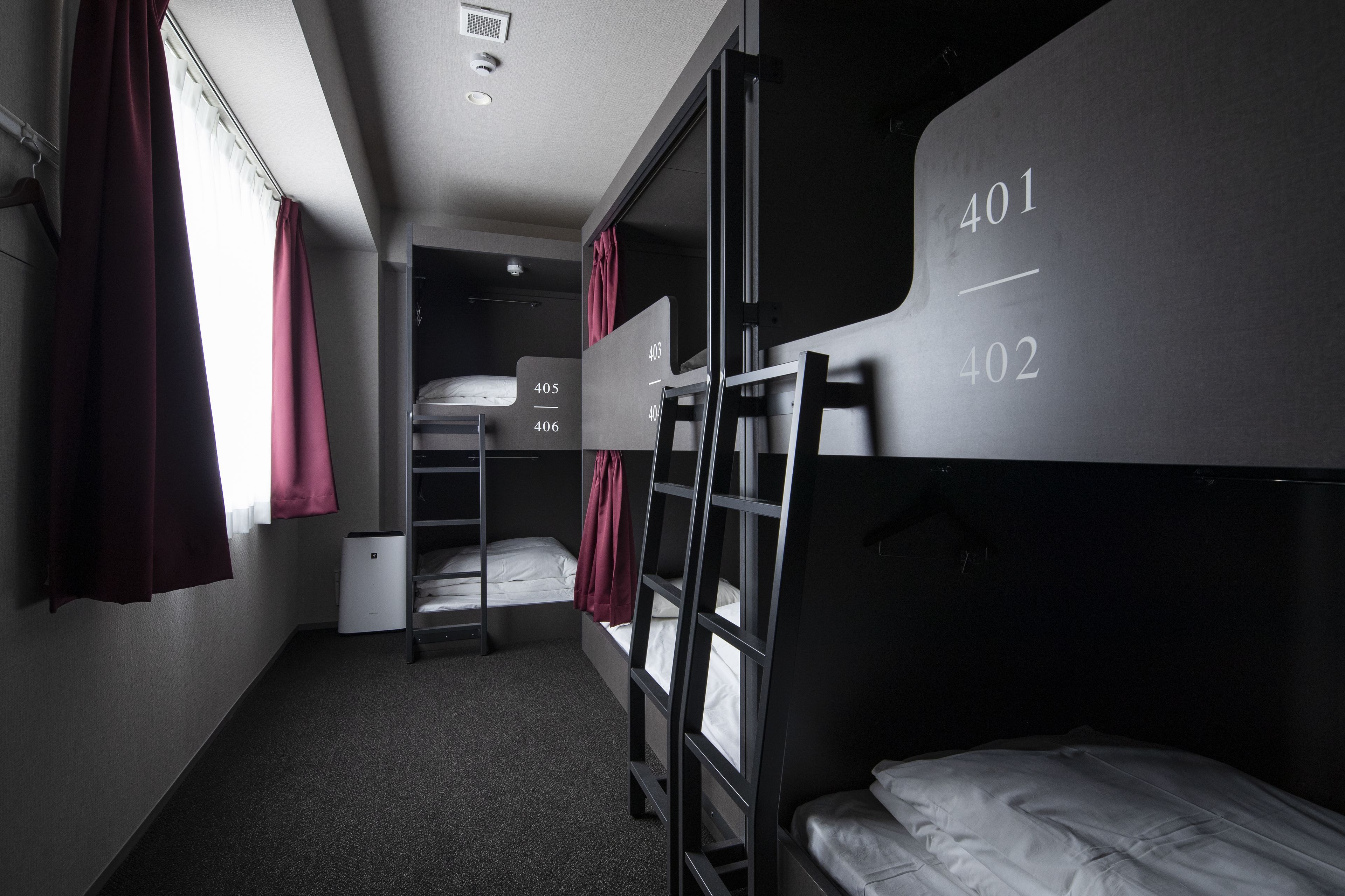 A dormitory room with bunk beds, numbered beds, and a small closet.