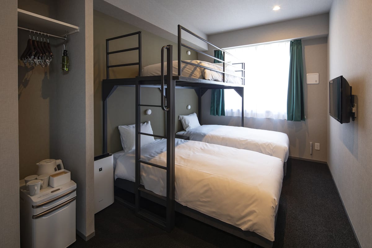Een slaapkamer met stapelbed, bureau en televisie.
