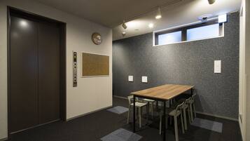 A conference room with a wooden table and chairs, an elevator, and patterned wallpaper.