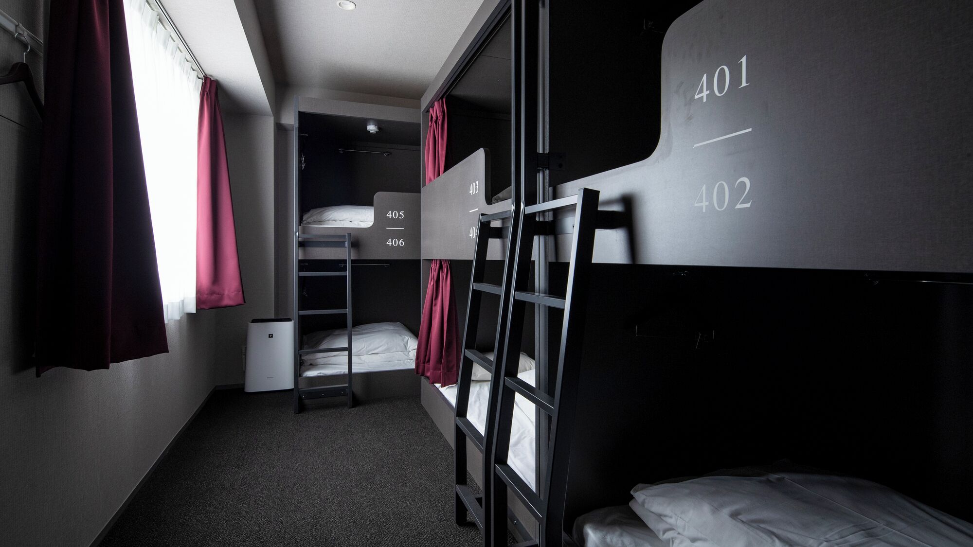 A bunk bed room with numbered beds, a small closet, and a window with curtains.