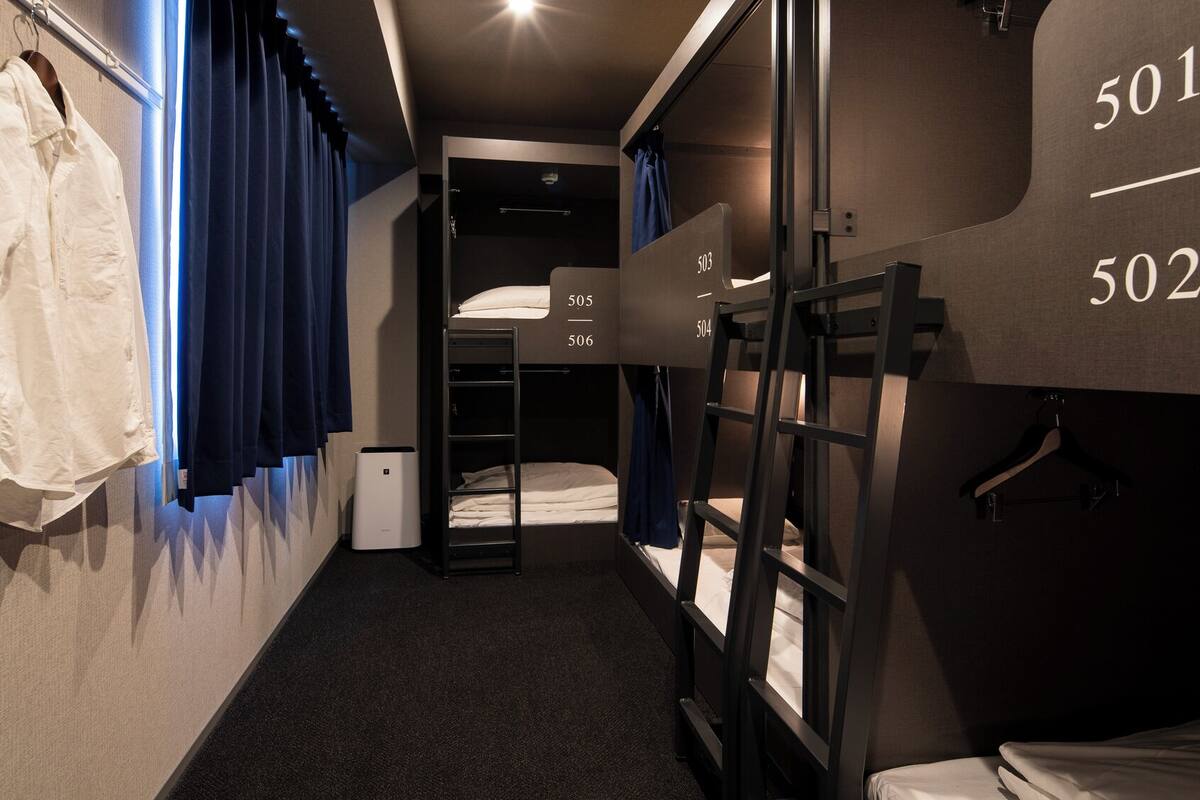 Een kleine hotelkamer met stapelbedden, een klein bureau en een kapstok.