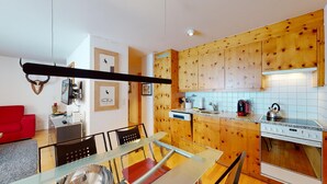 Eine moderne Küche mit Holzausstattung, integriertem Backofen und Essbereich mit Glastisch und Stühlen.