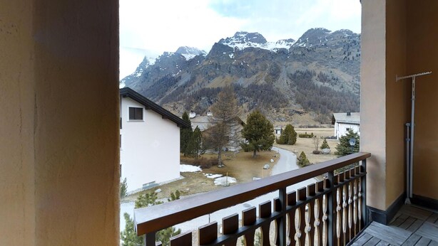 A balcony with a view of a mountain range and a small village. - Quiet 2-room apartment, ca. (Sils/Segl Maria)