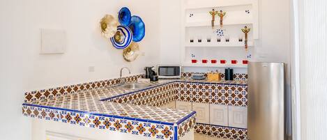 Een keuken met een centraal eiland, witte kasten, een roestvrijstalen koelkast en decoratieve muurkunst.
