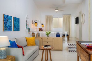 A modern living room with a sofa, coffee table, and a dining area with a kitchen counter.