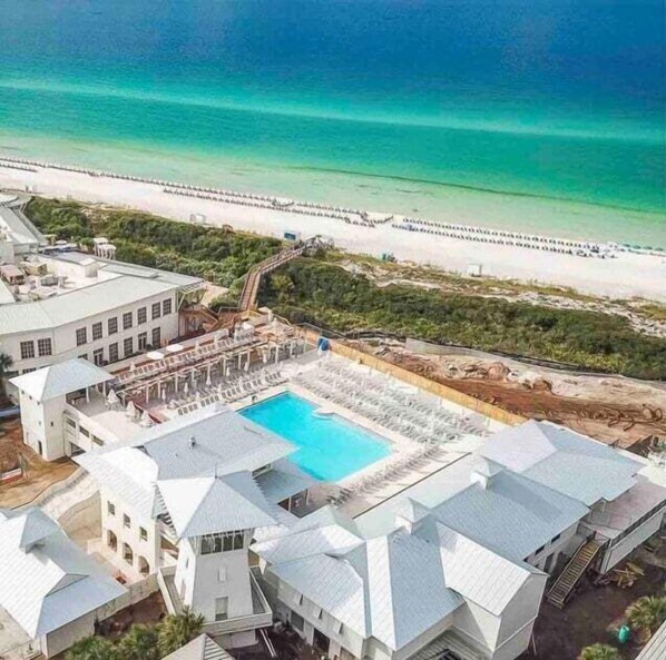 A resort with a swimming pool, beach access, and a large building with multiple rooms.
