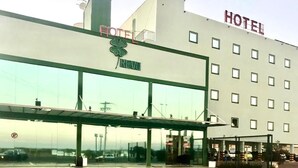 Un hotel con una amplia fachada de vidrio, una entrada cubierta y un letrero que indica que es un hotel.