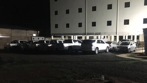 Un estacionamiento con varios coches aparcados frente a un edificio de varios pisos, de noche.