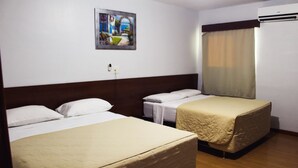 Habitación de hotel con dos camas, un cuadro en la pared, aire acondicionado y ventana con cortinas.