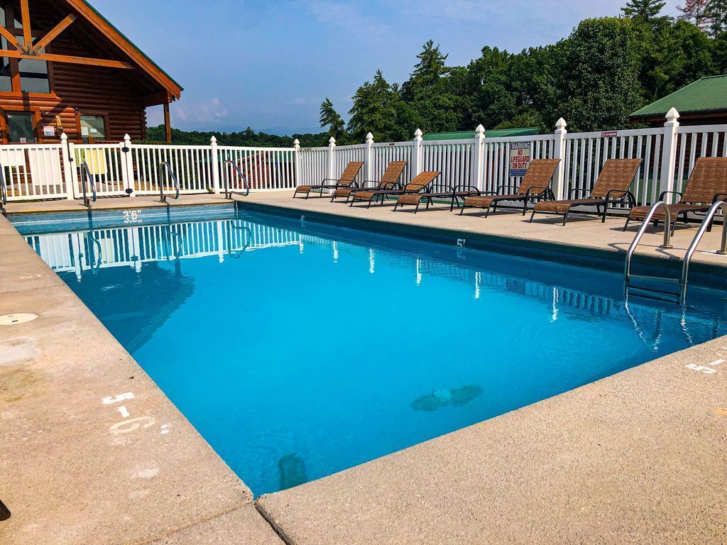 Une piscine avec des chaises longues et un chalet en bois en arrière-plan.