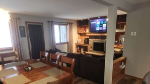 A cozy living room with a wooden dining table, chairs, a sofa, and a fireplace. - Killington Mountain View Townhouse (Killington)