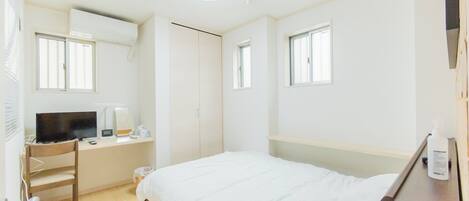 Un dormitorio con cama, escritorio, silla y televisor.
