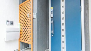Ein moderner Eingangsbereich mit blauer Tür, einem Holztor und einer weißen Wandklimaanlage.