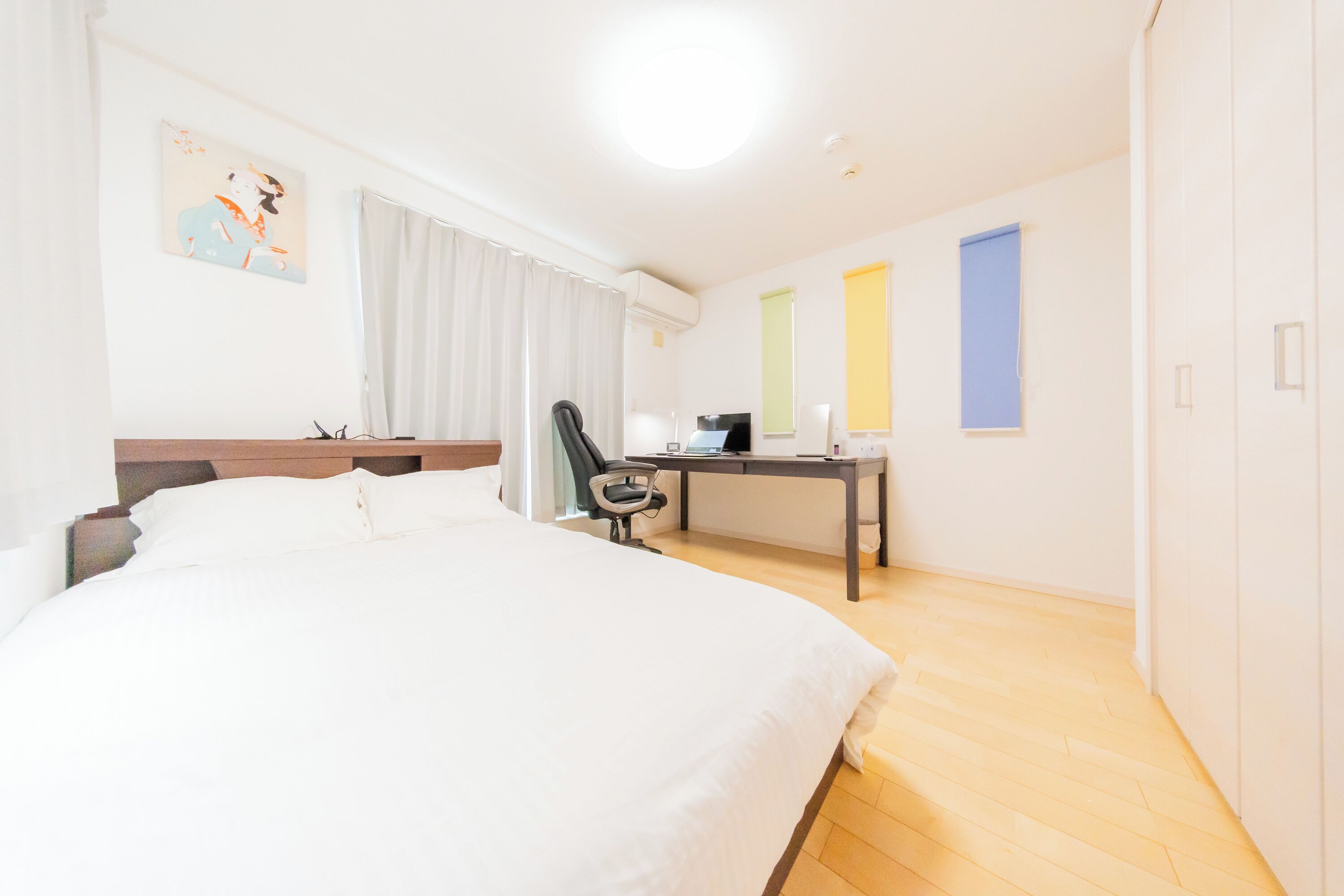 A hotel room with a large bed, a desk, a chair, and a window with curtains.