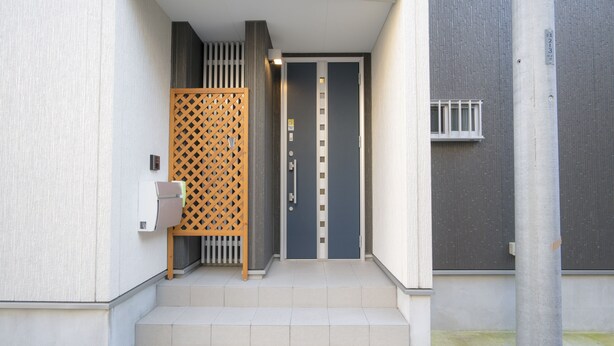 Ein Gebäudeeingang mit einem Holzzapfen und einer Treppe, die zu einer Tür führt, sowie ein kleines Fenster in der Wand.