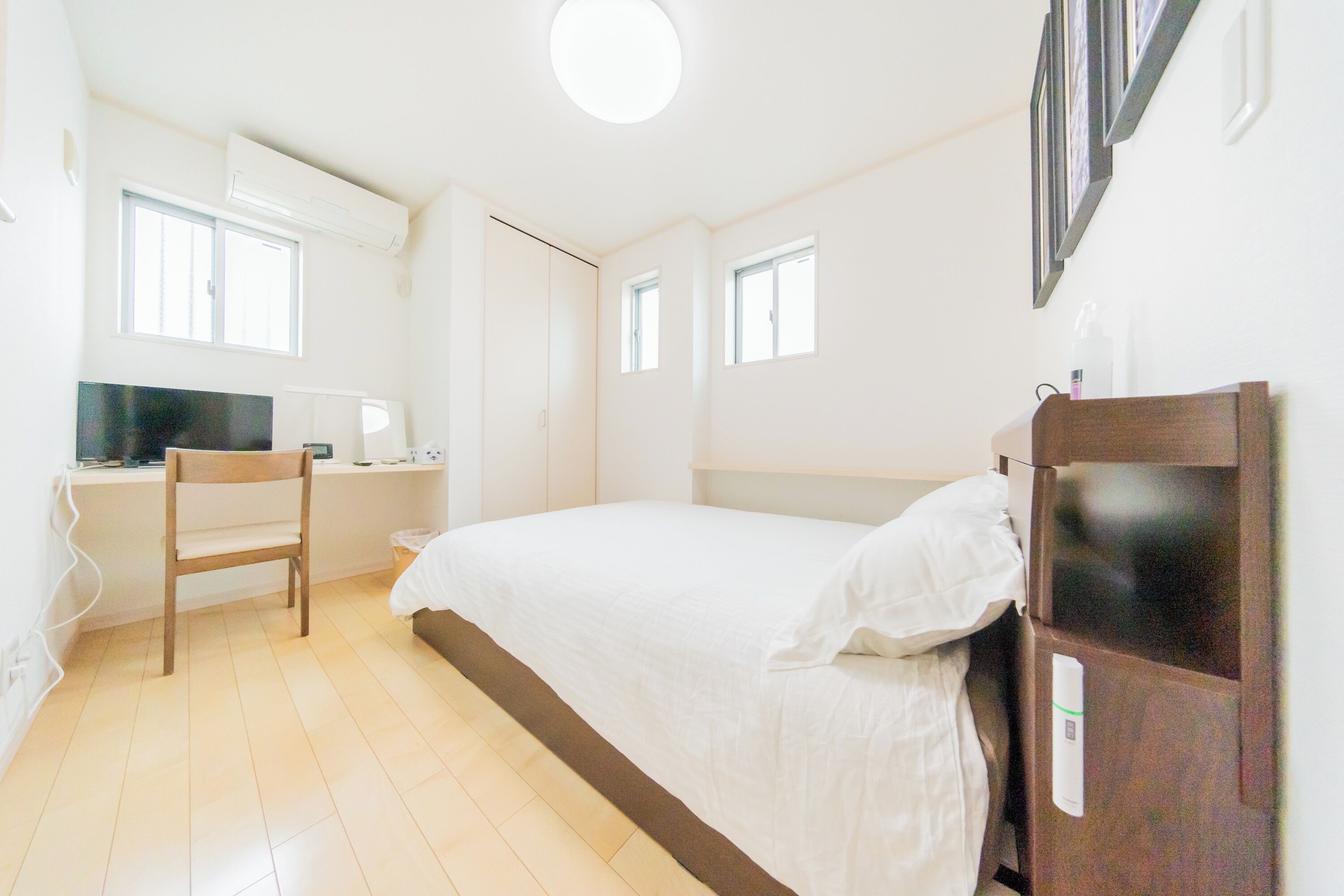 A bedroom with a bed, a desk, and a chair.