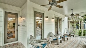 A covered porch with four Adirondack chairs, a ceiling fan, and a small table. - ‘FIVESEASONS’ Beautiful PET friendly HOME 🏖 2 POOLS * SHORT WALK TO BEACH  (Santa Rosa Beach)
