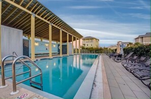 Relax by the pool surrounded by lounge chairs and umbrellas under a covered area with a roof.