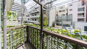 Un balcon doté d’une rambarde en métal, entouré d’immeubles et de lignes électriques.