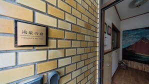 Un mur de briques sur lequel est apposée une enseigne indiquant « Ikebukuro No Yado ».