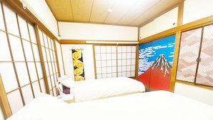 Une pièce de style japonais traditionnel, avec un sol recouvert de tatamis, un futon servant de lit, un paravent shoji et une fresque représentant le mont Fuji.