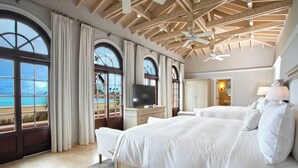 Ein geräumiges Schlafzimmer mit großen Bogenfenstern, einem Deckenventilator, einem Flachbildfernseher und einem großen Bett.