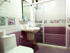 Un baño con inodoro, lavabo y zona de ducha.