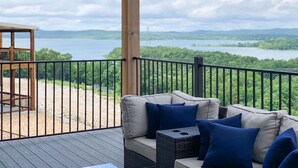A deck with a sofa and cushions, overlooking a lake and forested hills. - 10 bedrooms w/Swim/Spa - In/outdoor community pool (Branson)