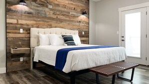 A bedroom with a wooden headboard, a bed with white bedding and a blue throw, a bedside table, and a bench. - 10 bedrooms w/Swim/Spa - In/outdoor community pool (Branson)