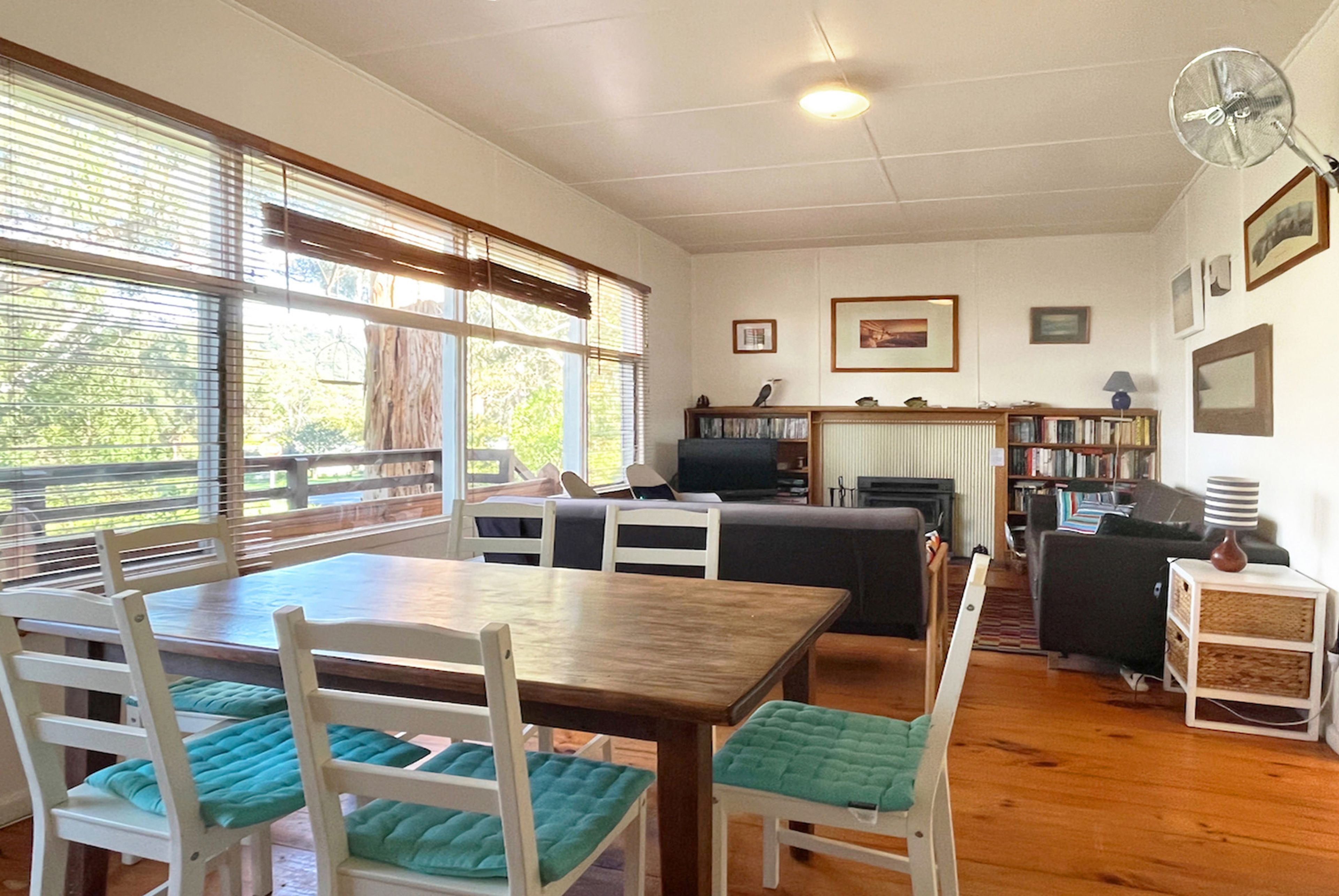 Une pièce comprenant une table à manger, des chaises, un canapé, un téléviseur et une bibliothèque.