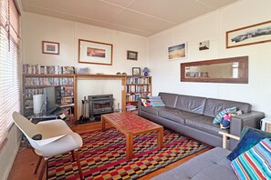 A living room with a fireplace, sofa, coffee table, and a bookshelf.