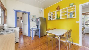 Een praktische keuken met eethoek, met een magnetron, koelkast en een klein tafeltje met stoelen.