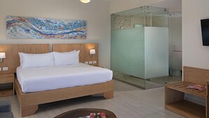 Een hotelkamer met een houten bed, een douchecabine van glas, een flatscreen televisie en een schilderij aan de muur.