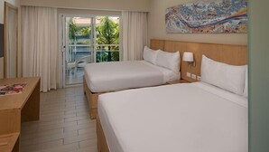 Een hotelkamer met twee bedden, een bureau, een televisie en een balkon met gordijnen.