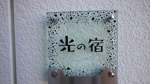 A glass sign with Japanese characters on a textured wall. - Hikari No Yado (Anan)