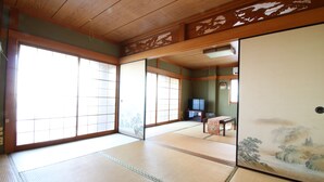 A traditional Japanese room with tatami flooring, sliding doors, and a television in the background. - Hikari No Yado (Anan)